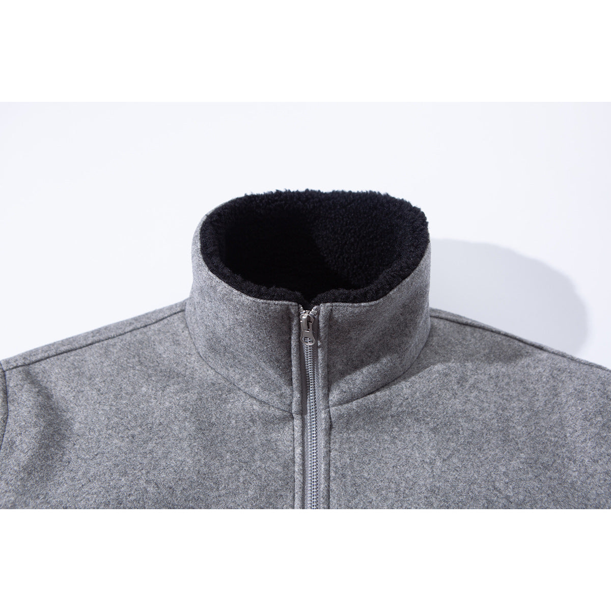 Close-up of a gray jacket's high stand collar with black plush lining and a front metal zipper.