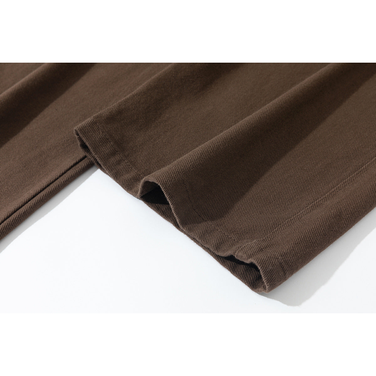 Close-up of the wide hems of brown pants, showing the fabric texture and stitching.