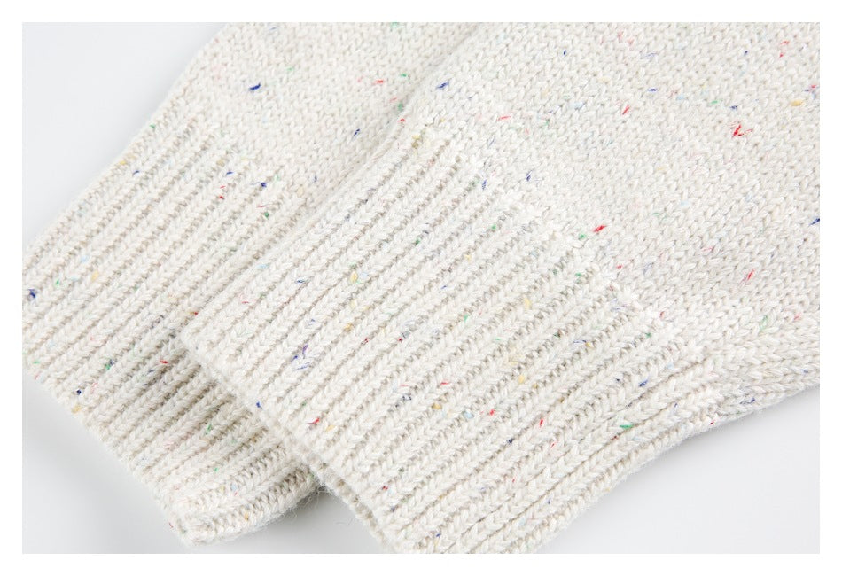 Close-up of a cream flecked knit sleeve ending in a thick ribbed cuff.