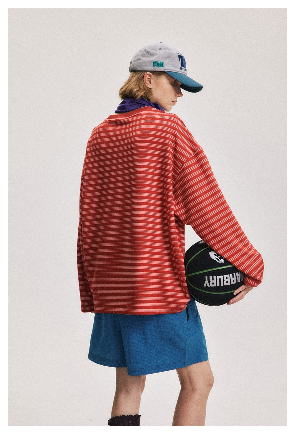 Model turned away to show the back of an oversized red shirt with thin white stripes.