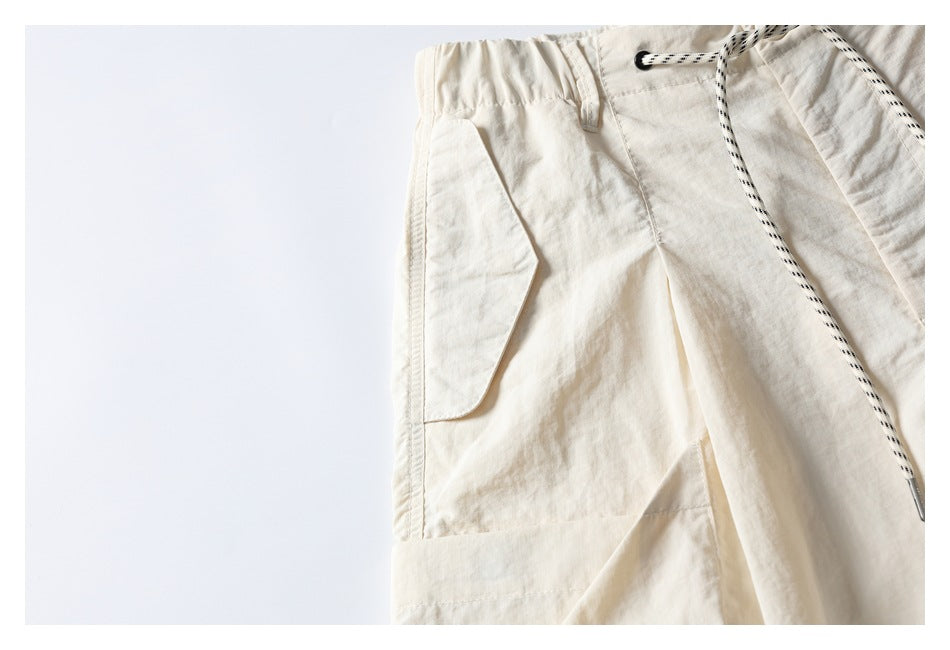 Close-up of off-white shorts showing the large side cargo pocket, panel seams and black-and-white drawcord.