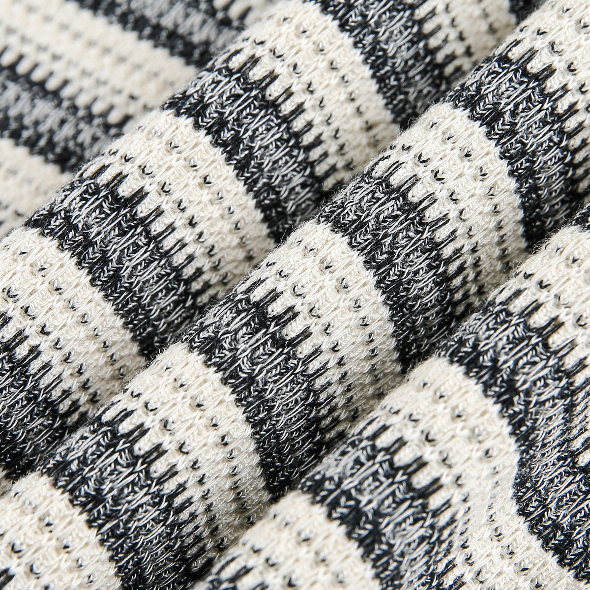 Macro view of the raised black-and-cream striped knit texture on a garment.