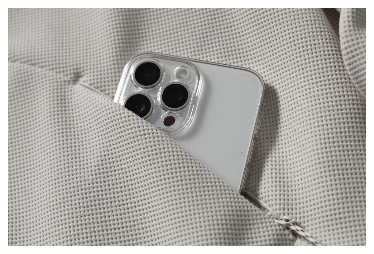 A smartphone tucked into a pocket in the off-white textured jacket.