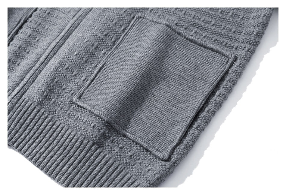 Close-up of a gray textured cardigan's rectangular rib-knit pocket, zipper, and ribbed hem.