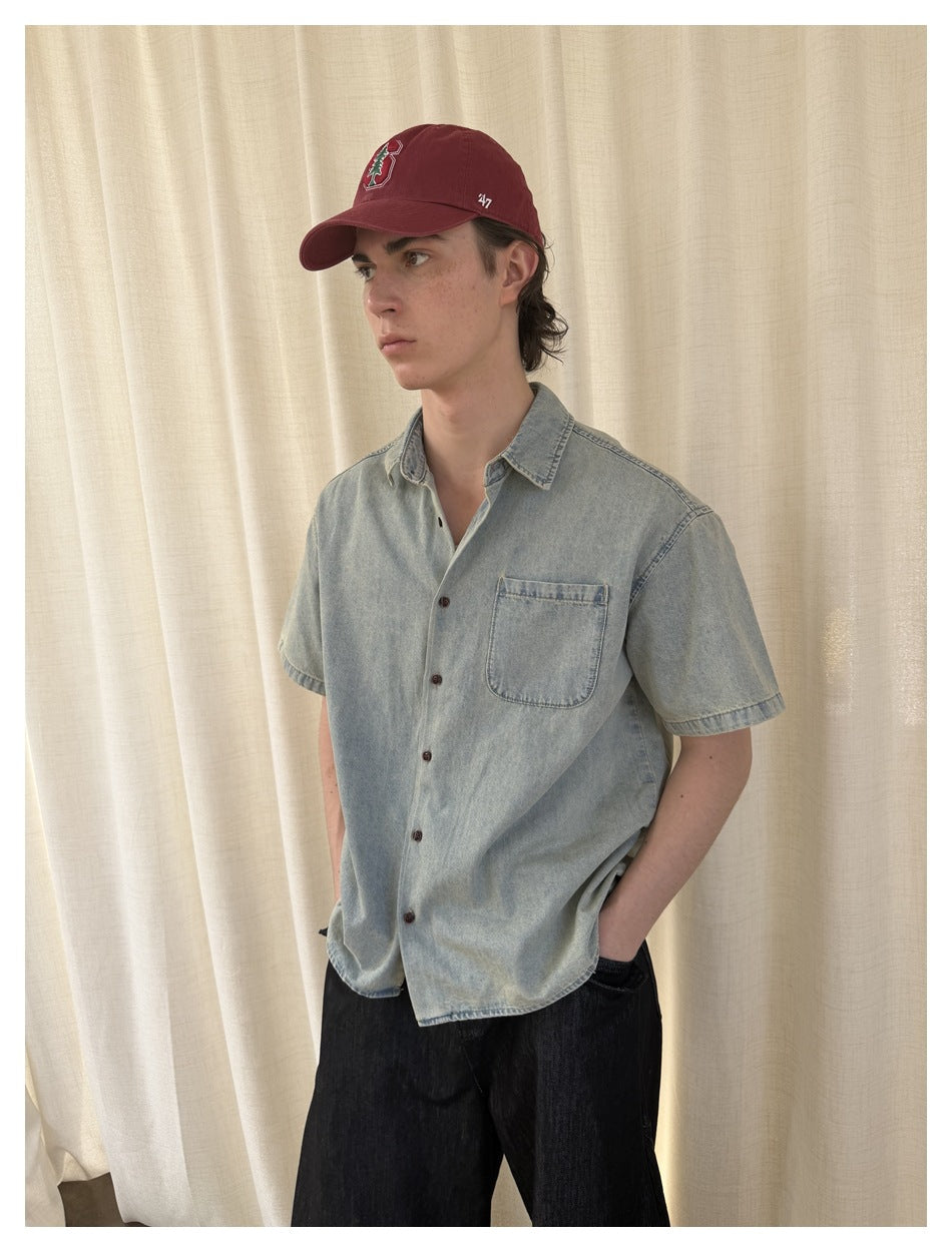 Three-quarter view of a model in a pale washed-blue short-sleeve button-up shirt with a chest pocket.