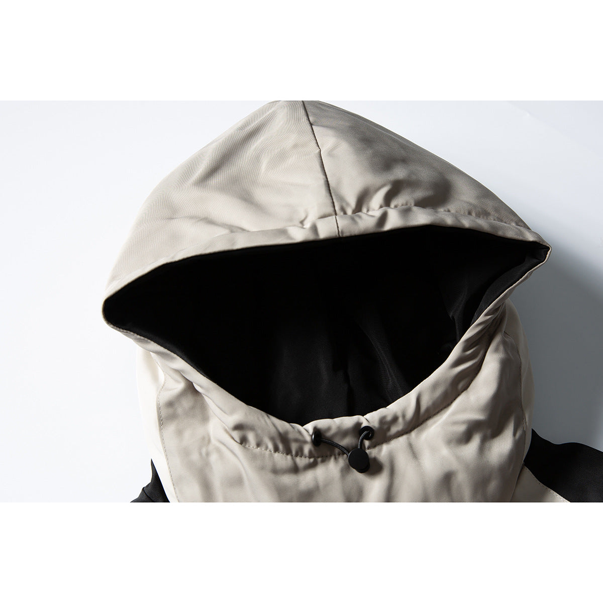 Close-up of a light taupe hood with black lining and a black drawcord adjuster.