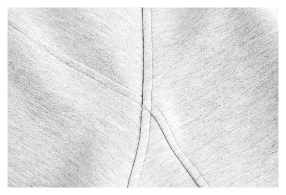 Close-up of stitched panel seams on light gray heather hoodie fabric.