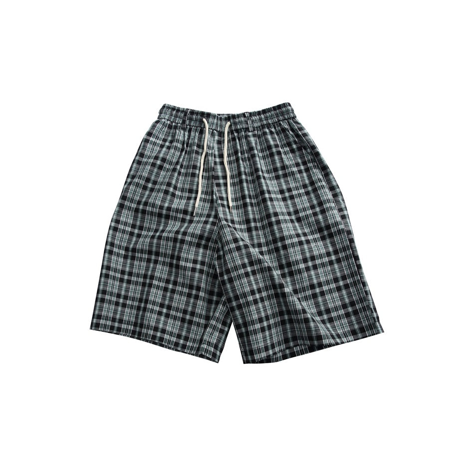 Green and black plaid knee-length shorts with elastic waist and off-white drawstring, flat lay front view