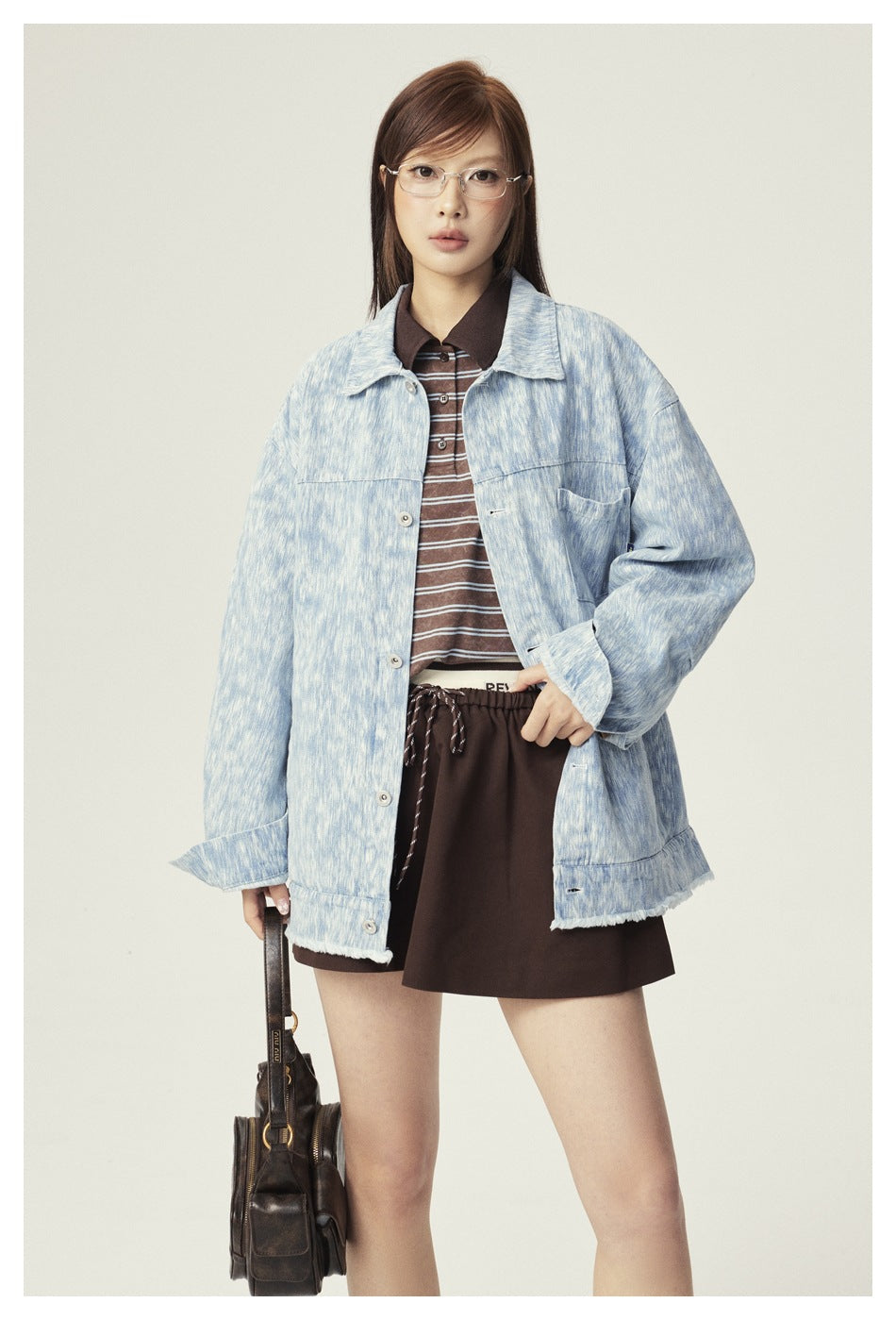 Front view of a model wearing an oversized light blue patterned jacket with button front and chest pocket.