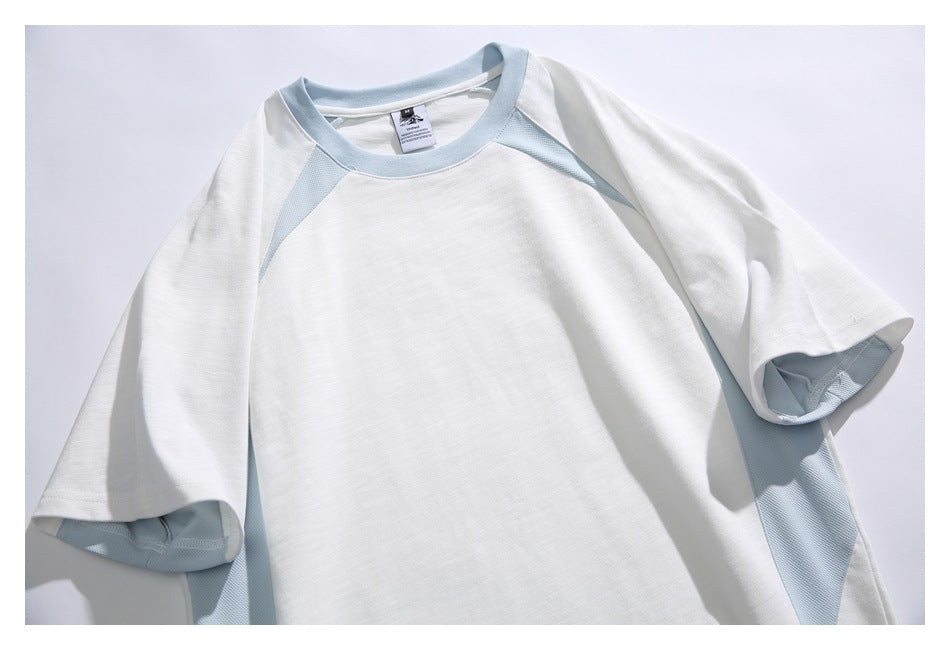 Close-up of a white T-shirt with pale blue raglan trim at the collar, shoulders, and side panels.