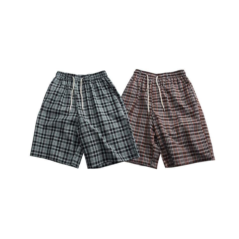 Front view of plaid shorts in dark green-gray and brown colorways, both with elastic waists and drawstrings.