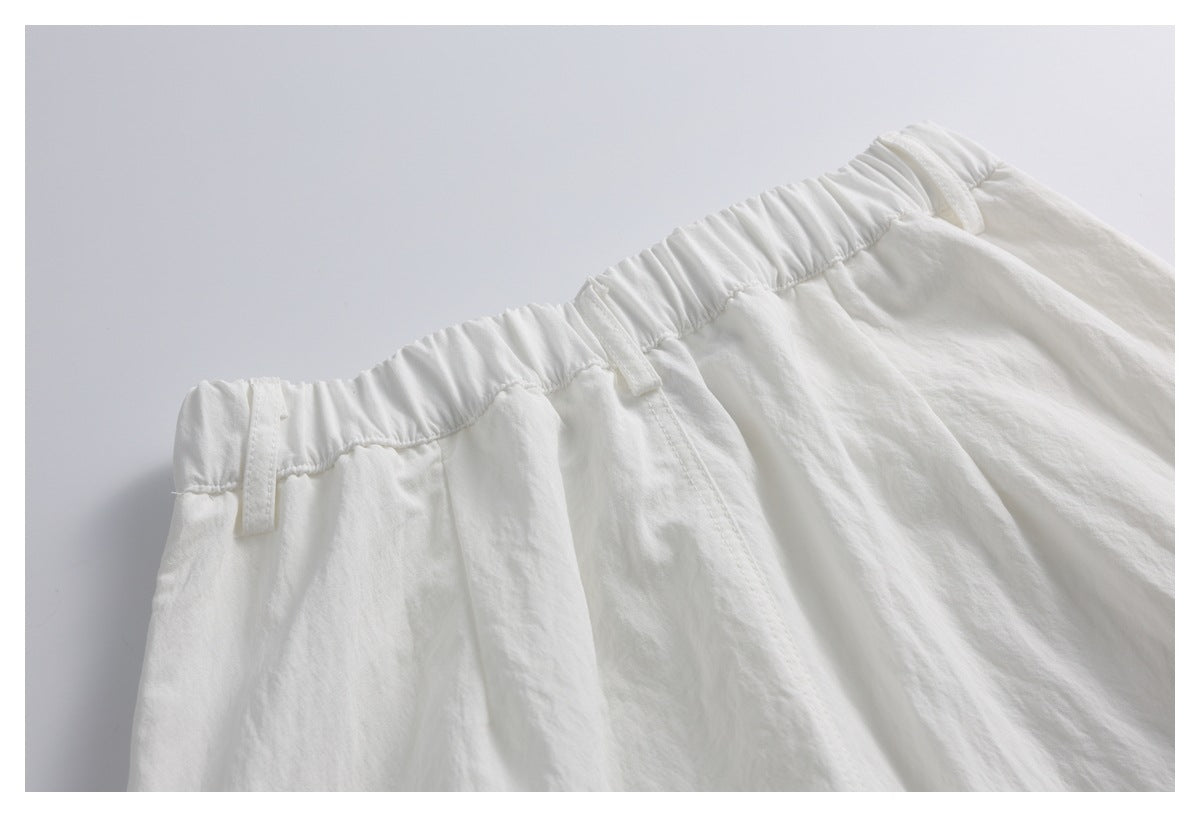 Close-up of white shorts with a gathered elastic waistband and belt loops.