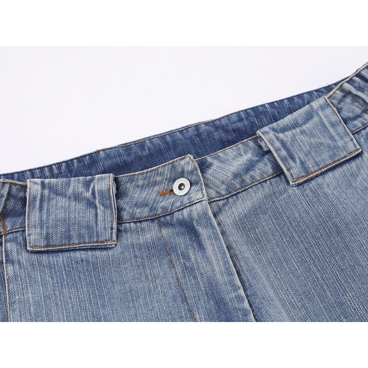 Close-up of the front waistband and belt loops of faded blue jeans, showing the button and stitching.