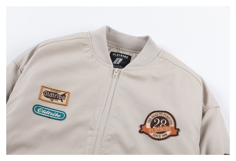 Close-up of a light beige jacket front with a zipper and several colorful embroidered patches.