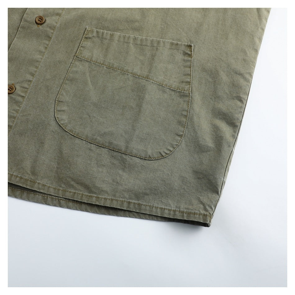 Close-up of an olive-gray garment's large patch pocket, button placket, and hem.