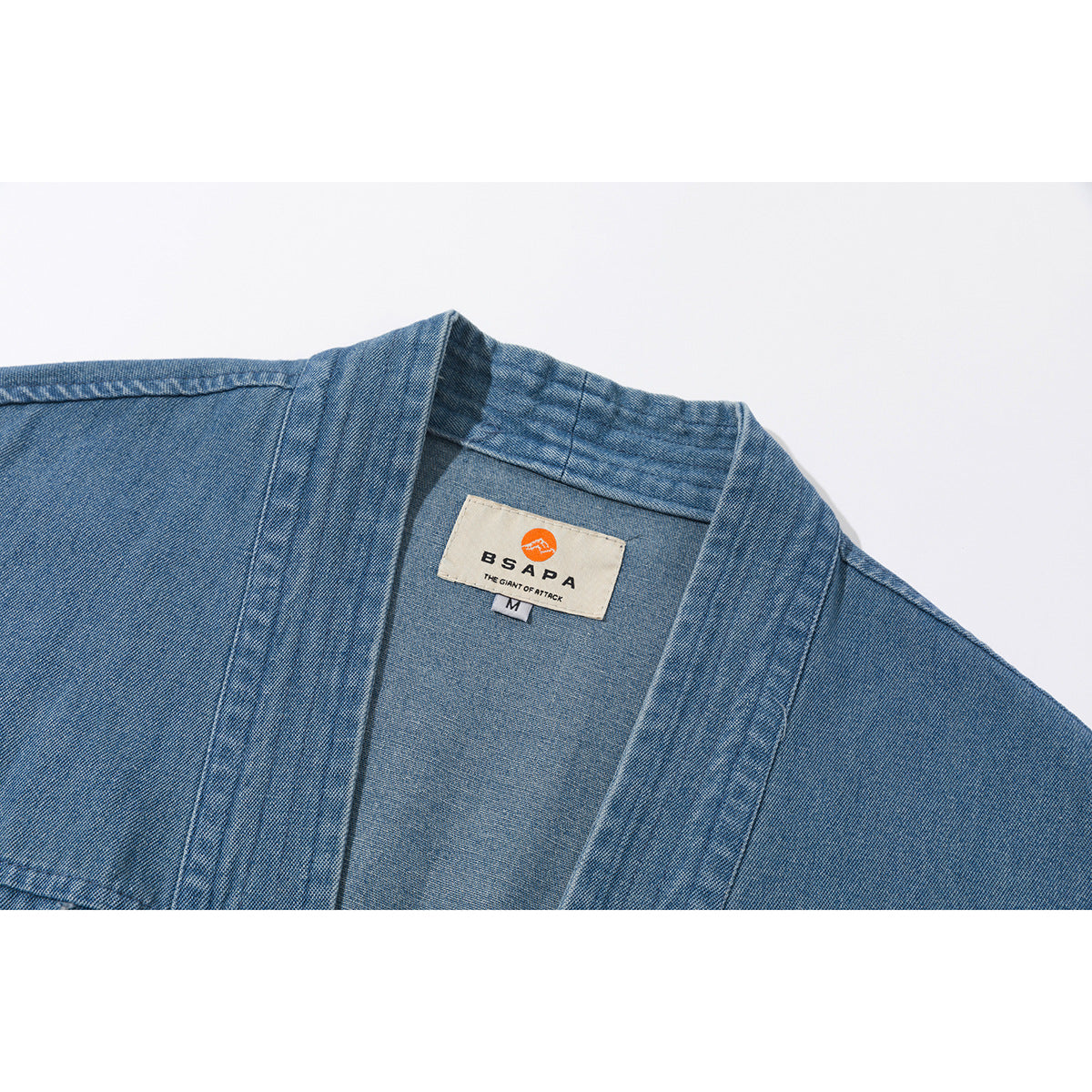 Close-up of a blue denim wrap garment's collar and sewn-in neck label.