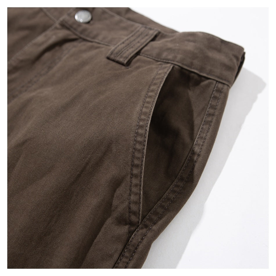 Angled close-up of a side pocket opening and waistband on dark brown trousers.