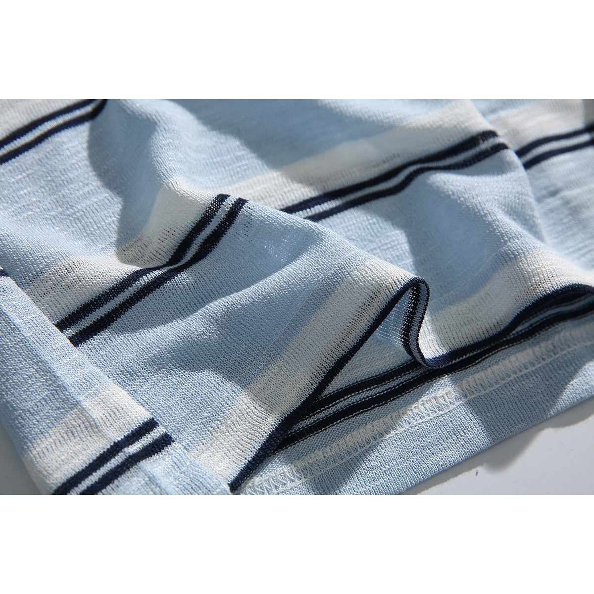 Close-up of the pale blue striped knit fabric, folded hem, and stitching.