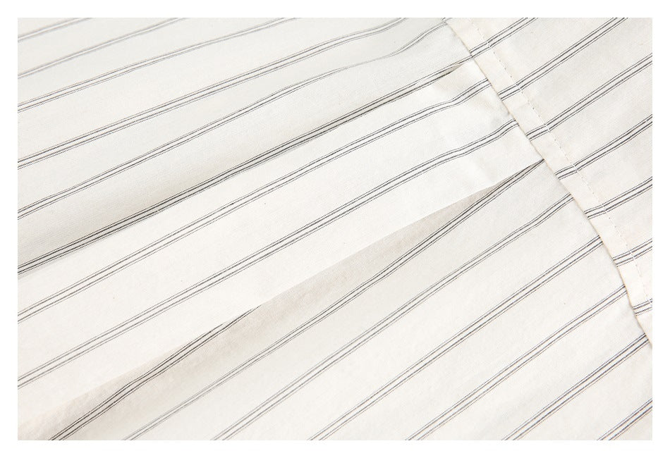 Close-up of thin dark stripes and a stitched seam on off-white shirt fabric.