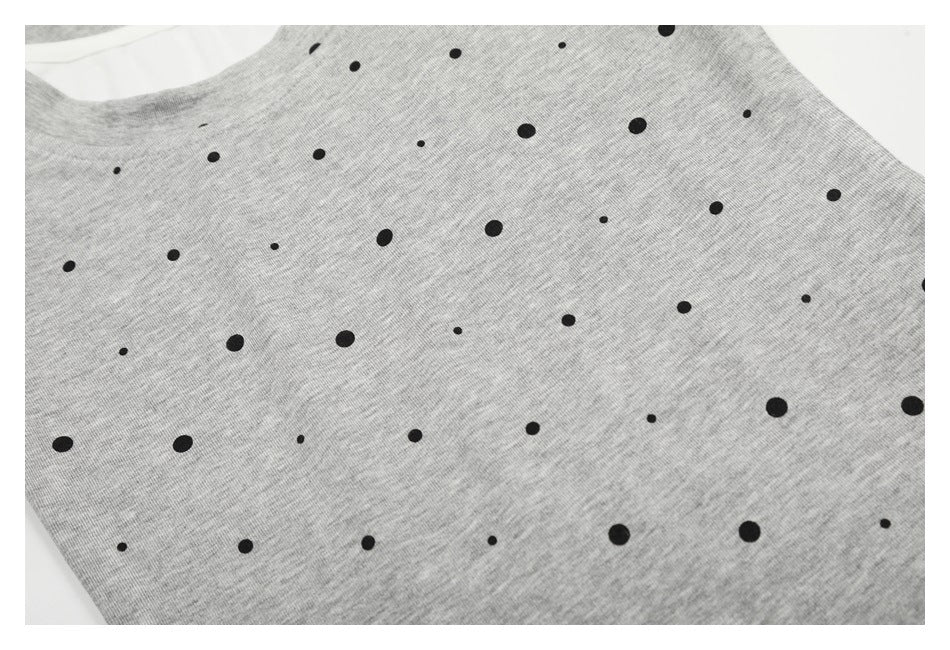 Close-up of scattered black dots across the gray T-shirt fabric.