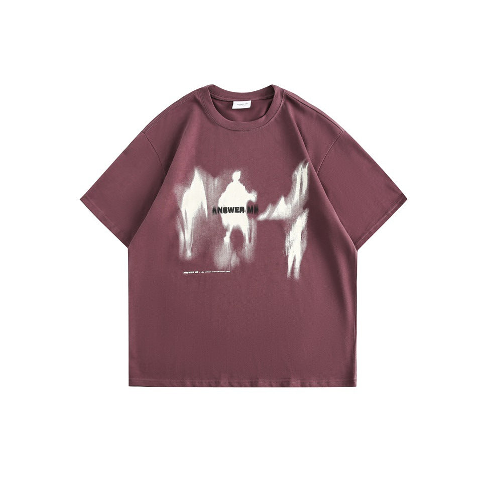 Purple short-sleeve crew-neck T-shirt with blurred white figure graphic and black 'ANSWER ME' lettering, flat lay