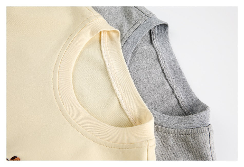 Close-up of the crew neck and shoulder seams on pale yellow and heather gray T-shirts.