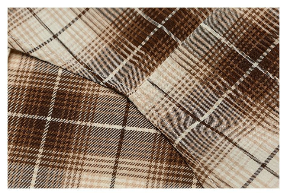 Close-up of overlapping brown and cream plaid shirt panels and their stitched seam.