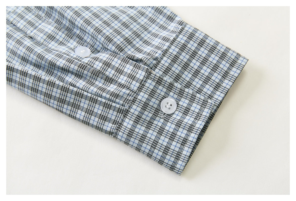 Close-up of the plaid shirt cuff with two white buttons and matching black and pale blue checks.