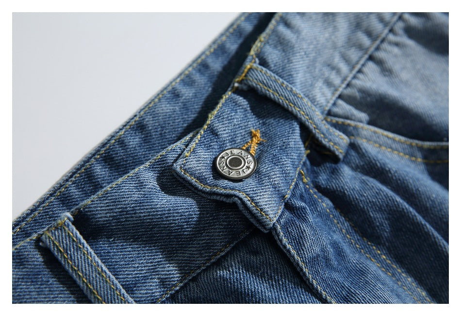 Close-up of the jeans' metal waistband button and yellow topstitching.