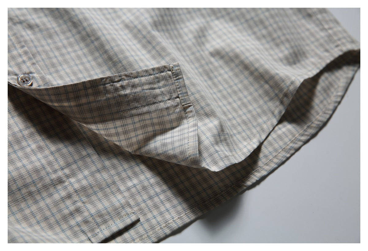 Close-up of a beige plaid shirt's sleeve cuff and curved hem.