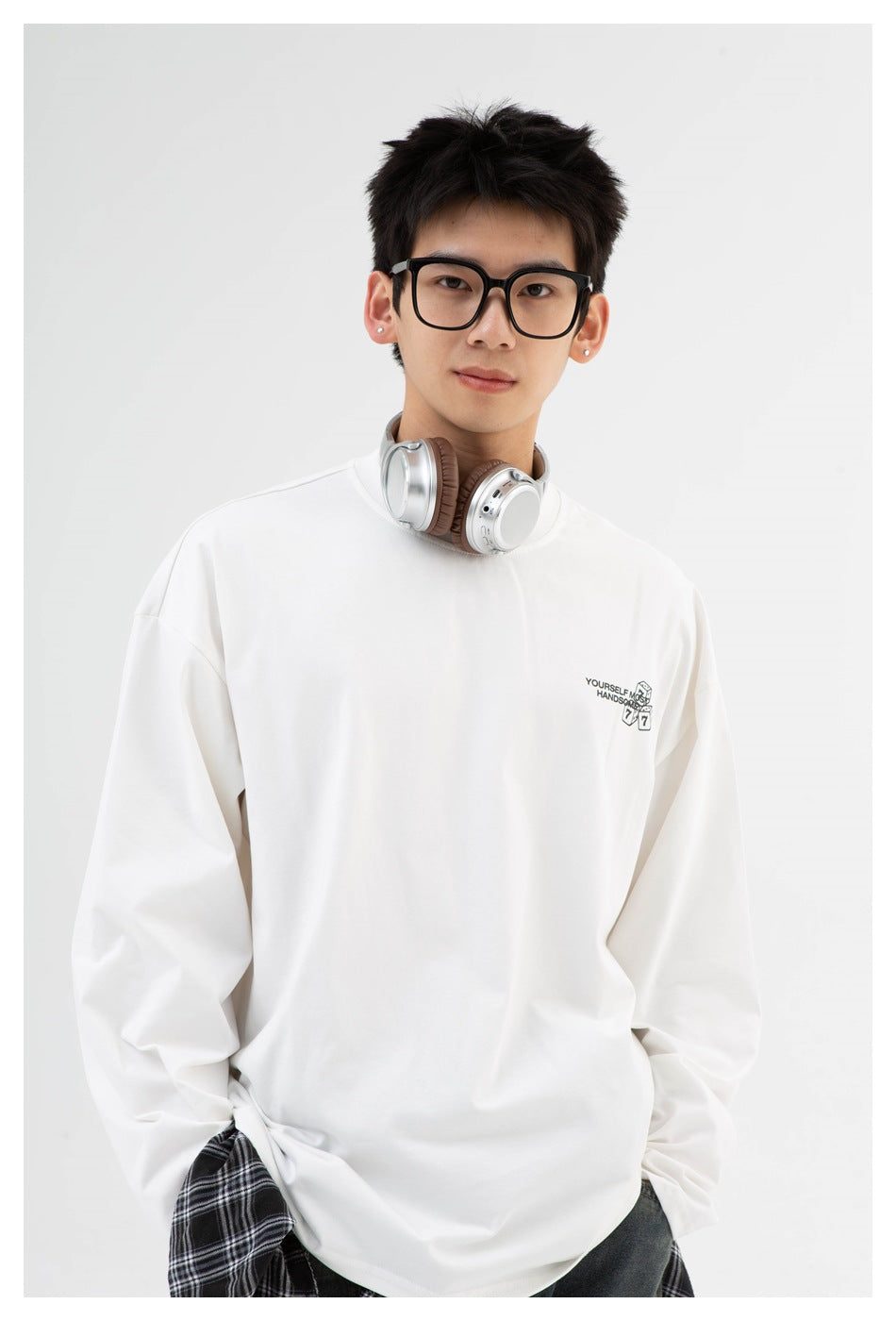 Front view of a model in an oversized white long-sleeve shirt with a small black dice graphic on the chest.