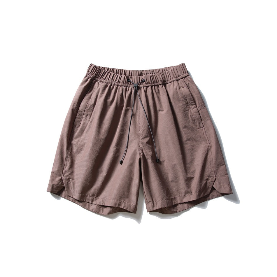 Mauve brown drawstring shorts with elastic waistband, side pockets and curved side-slit hems, flat lay