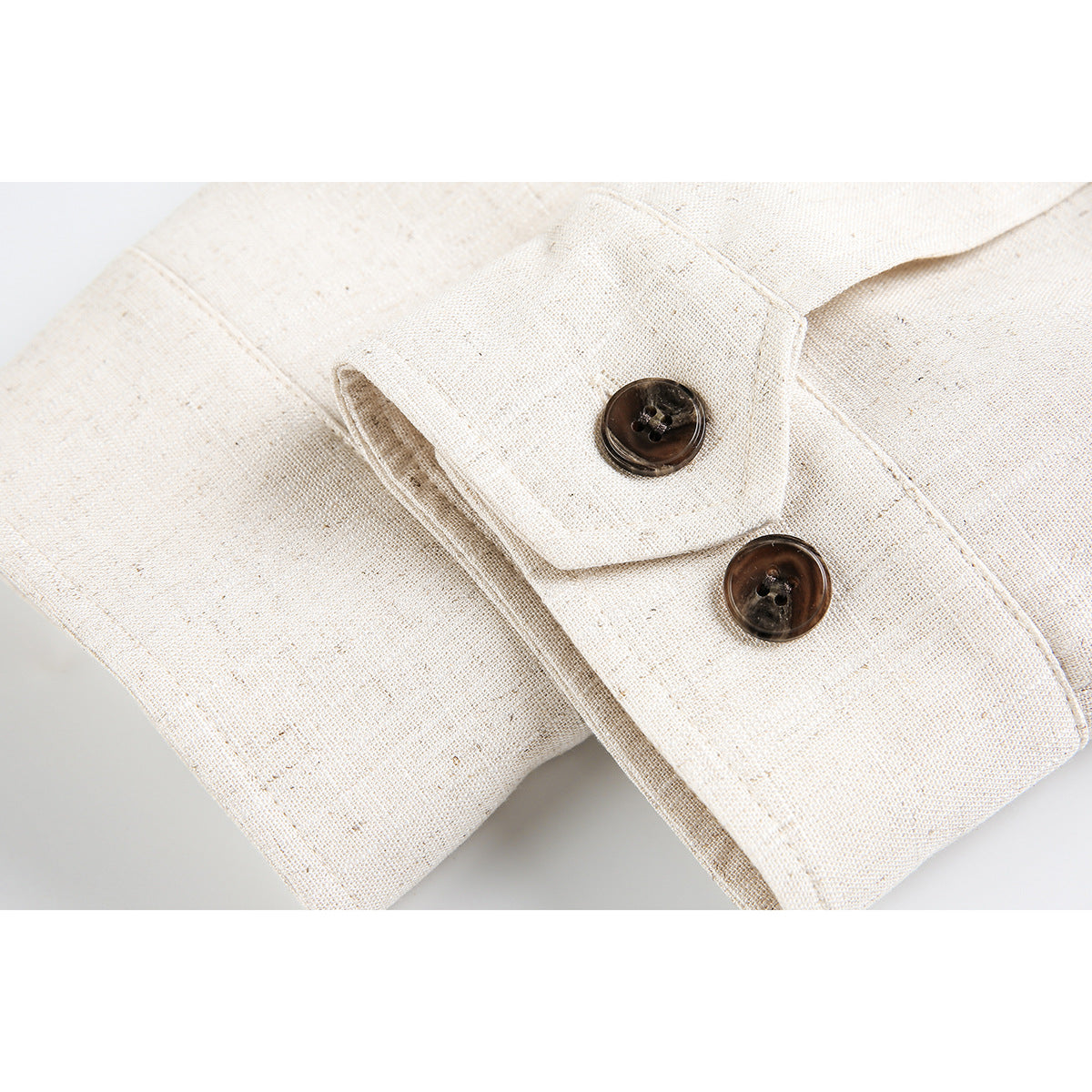 Close-up of a cream jacket cuff with a buttoned tab and dark brown buttons.