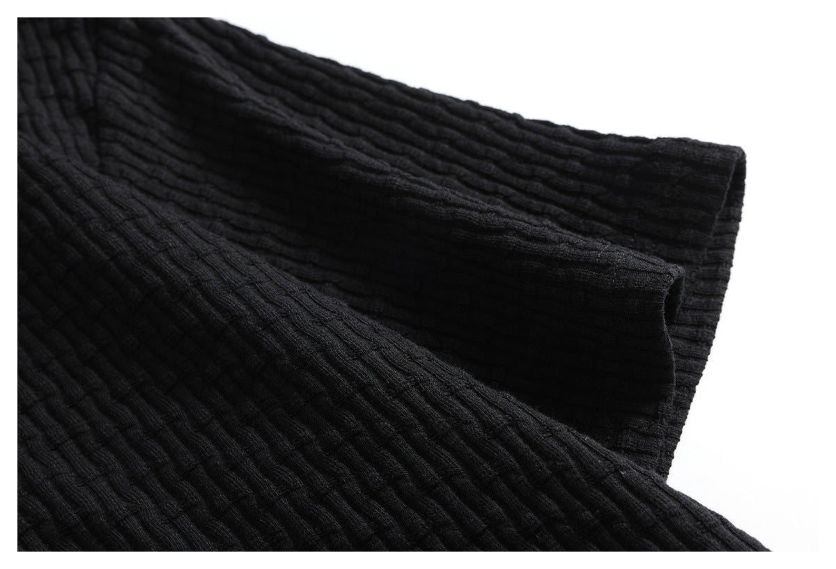 Close-up of the black ribbed garment's folded sleeve and cuff.