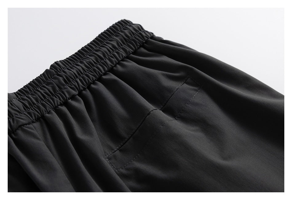 Close-up of the gathered elastic waistband and a slanted pocket on black pants.
