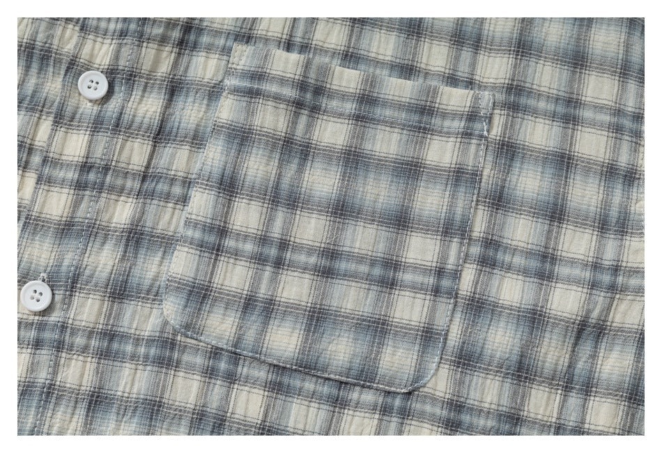 Close-up of the plaid shirt’s chest pocket, stitching, and white buttons.