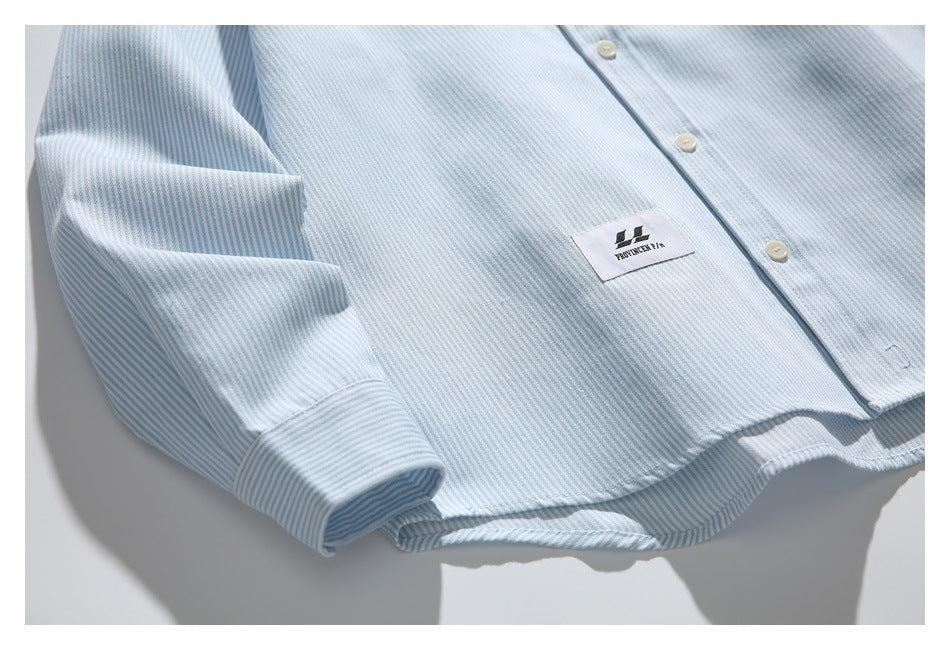 Close view of the striped shirt front, sleeve cuff, buttons, and a small sewn logo label.