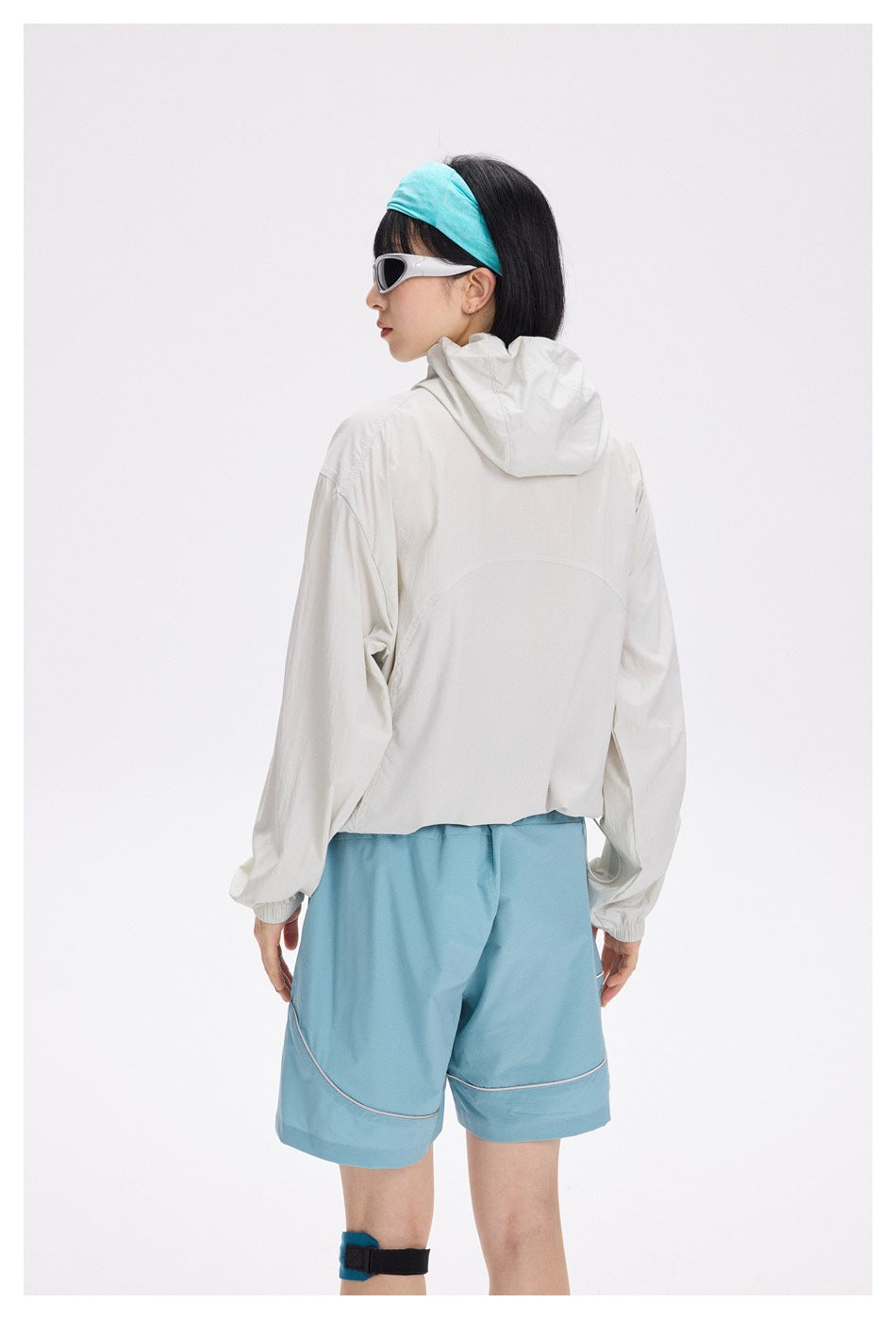 Back view of a model wearing an off-white hooded jacket and light blue shorts.