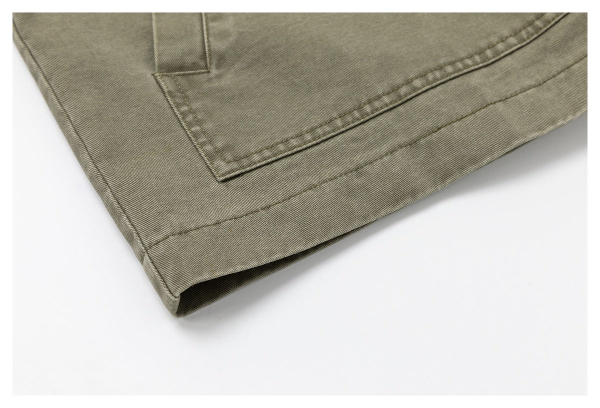 Close-up of an olive-gray garment hem with a stitched pocket edge and layered seams.