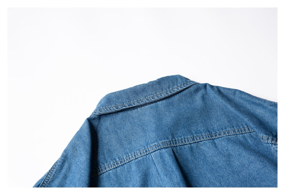 Cropped flat lay of the upper back of a blue denim shirt, showing its collar and yoke.