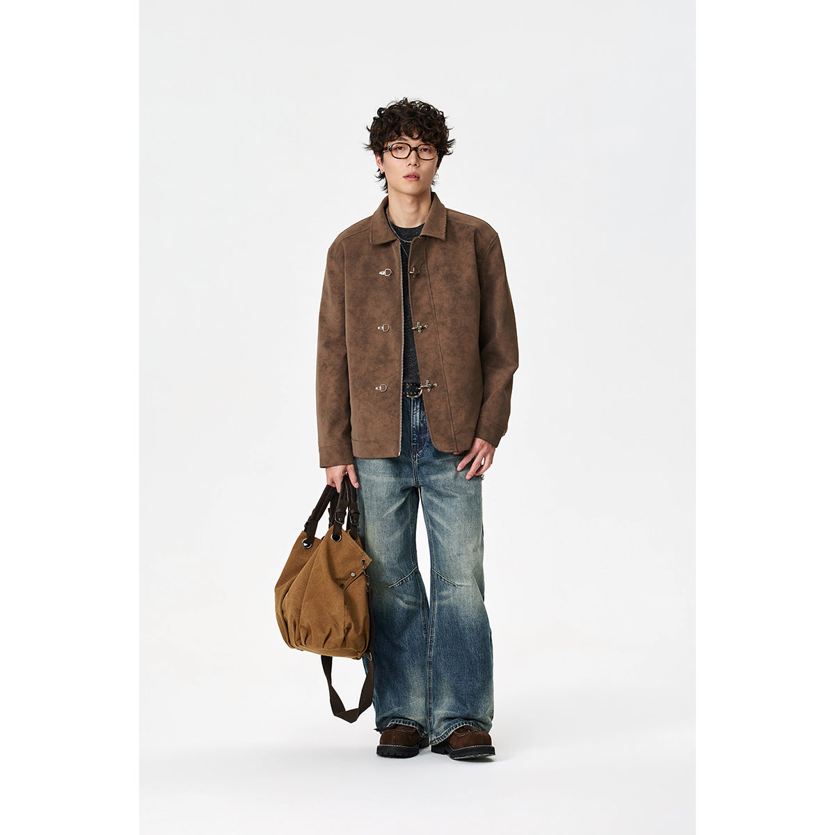 Full-length view of a model wearing a brown collared jacket with metal toggle closures and wide blue jeans.