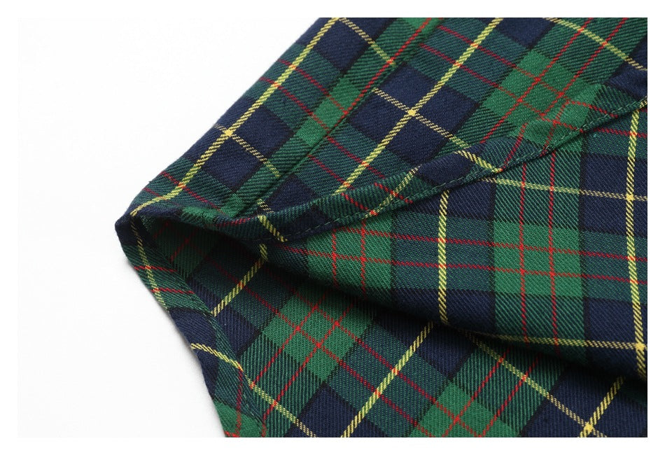 Close-up of overlapping stitched seams on the green and navy tartan shirt.