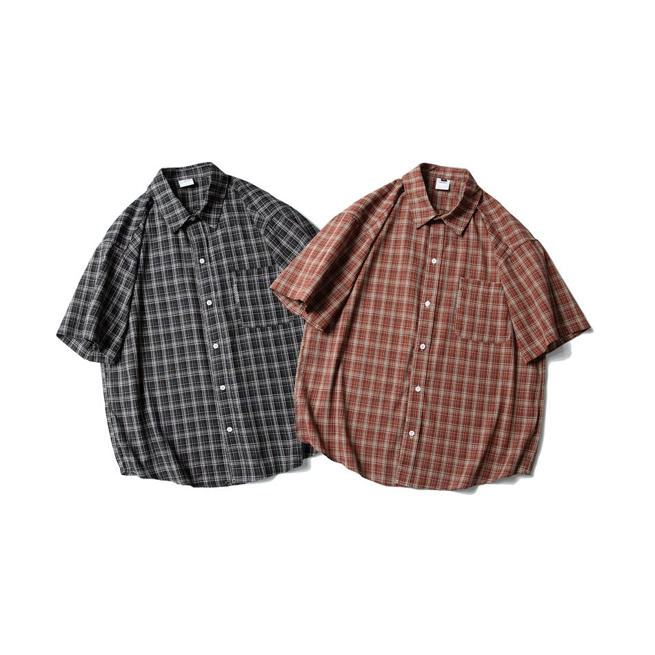 Two short-sleeve button-up shirts laid flat: one black-and-gray plaid and one rust-red plaid, both with chest pockets.