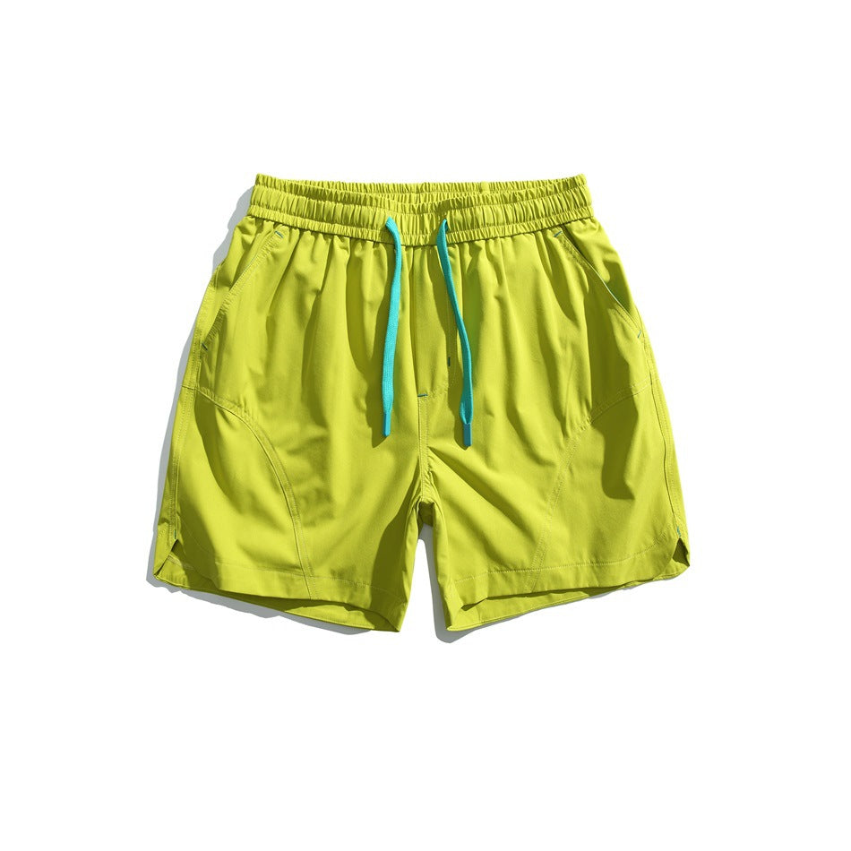Yellow-green drawstring shorts with teal cords, curved panel seams and curved side hems, flat lay front view