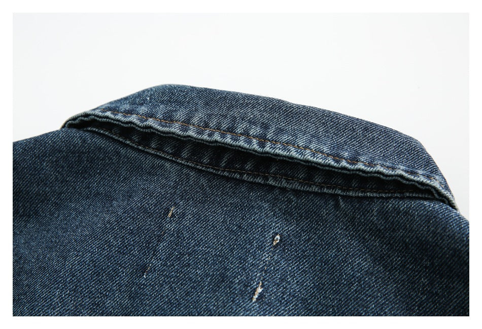 Close-up of a blue denim seam with contrast stitching and small distressed marks.