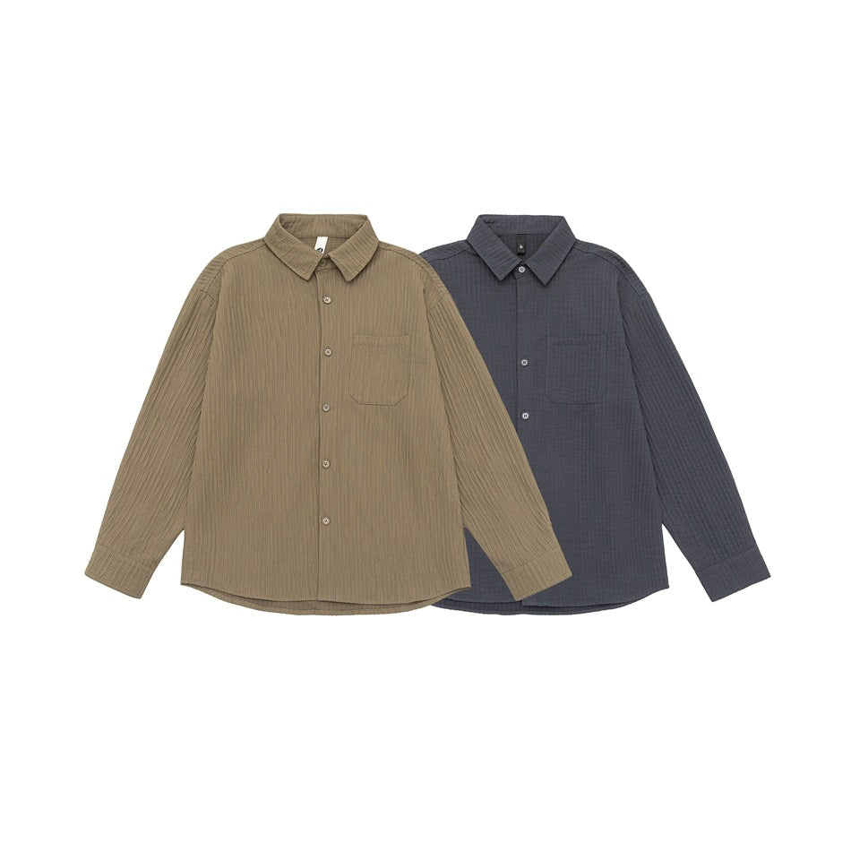 Two button-up overshirts shown from the front in taupe brown and charcoal, each with a chest pocket and vertical texture.