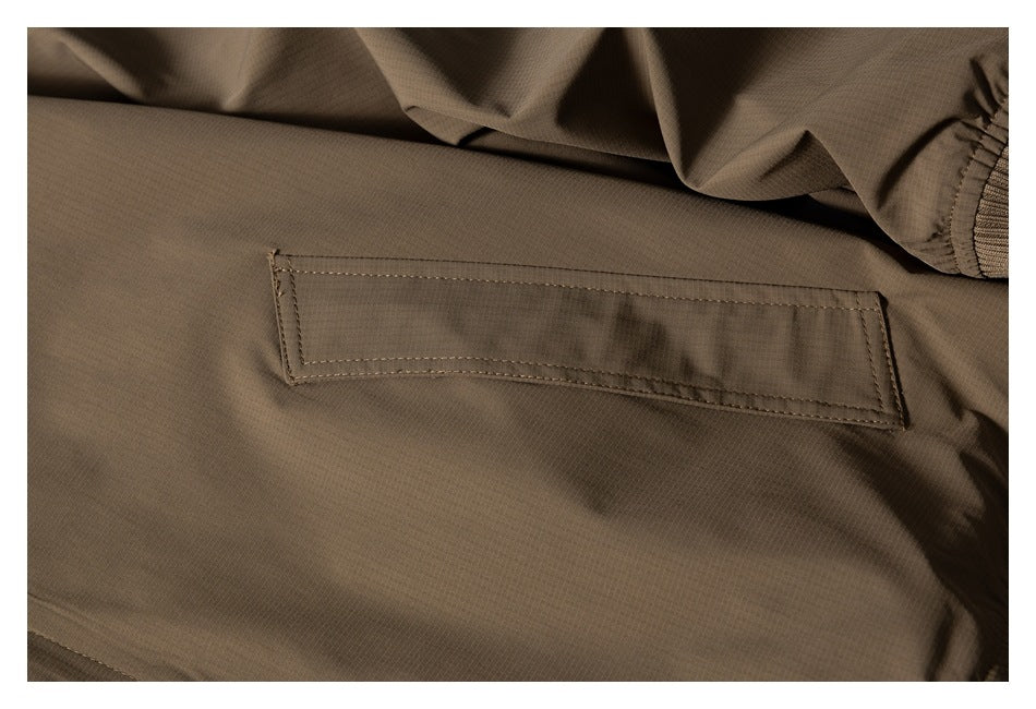 Close-up of a rectangular stitched pocket on the brown jacket, with a ribbed edge visible.