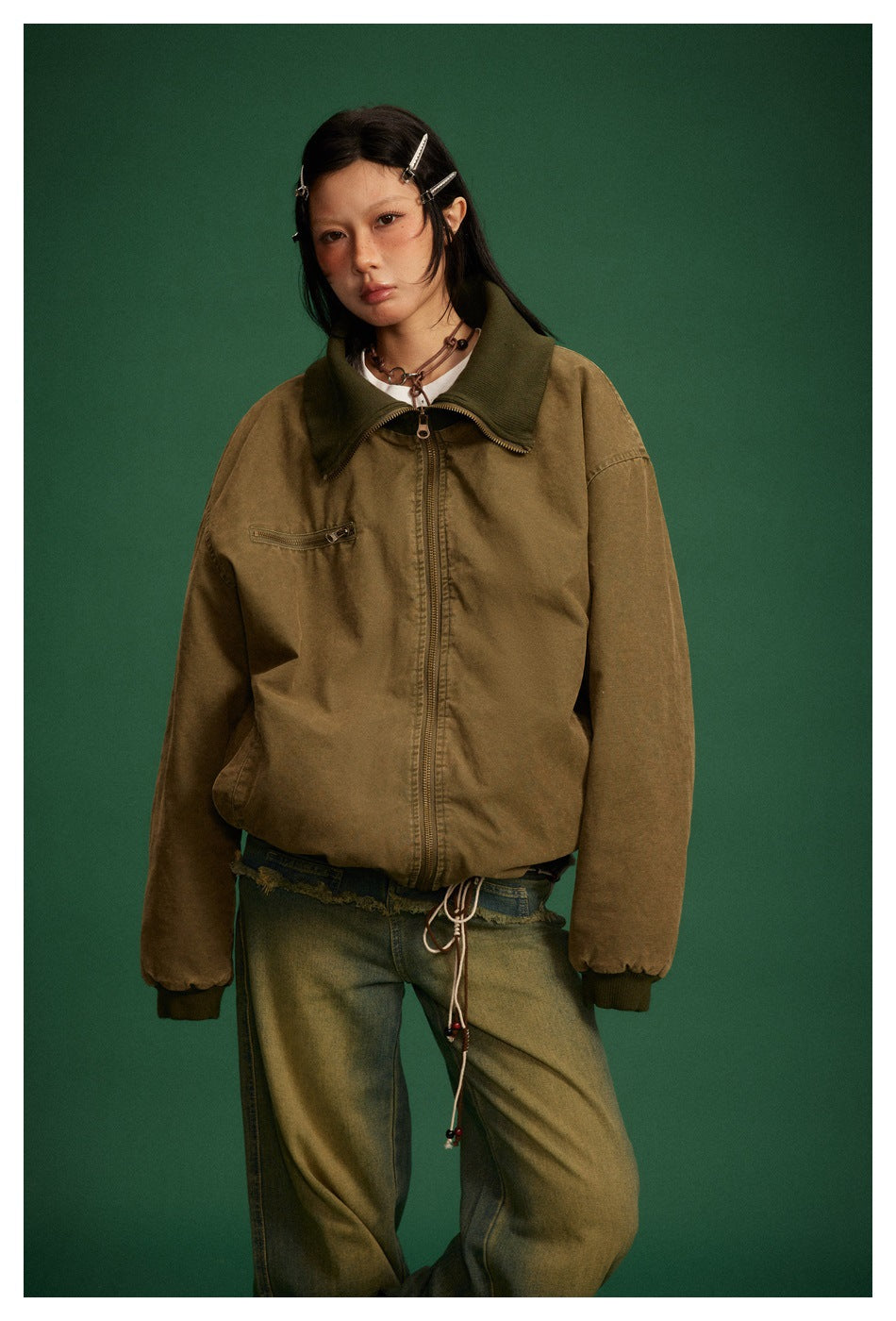 Front view of a model wearing an olive-brown zip jacket with a wide dark ribbed collar and chest pocket.