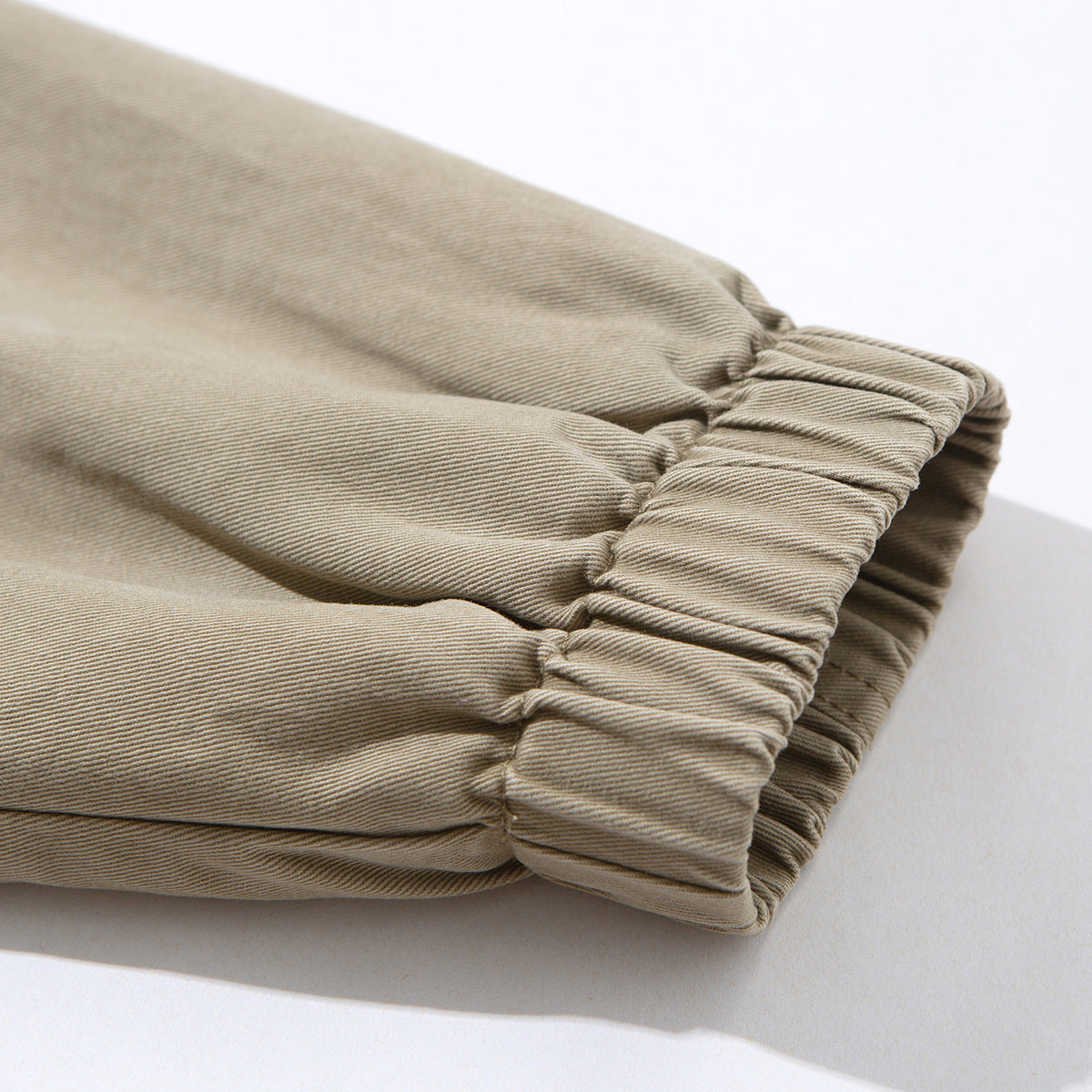Close-up of a taupe jacket sleeve gathered into a stitched elastic cuff.