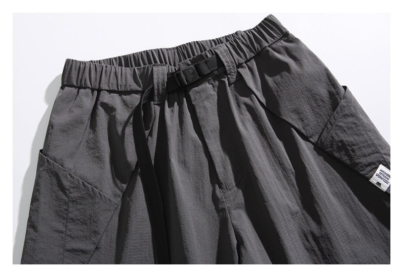 Close view of charcoal gray shorts with an elastic waist, black buckle belt, and large side pockets.